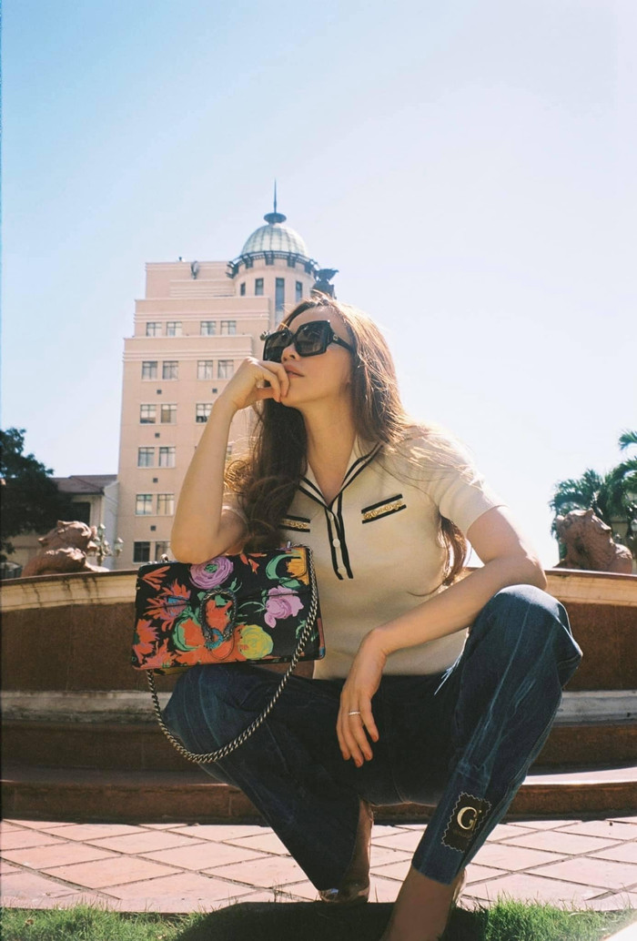 Cô kết hợp áo phông với kiểu quần jeans sẫm màu kết hợp với phụ kiện túi xách và kính mát