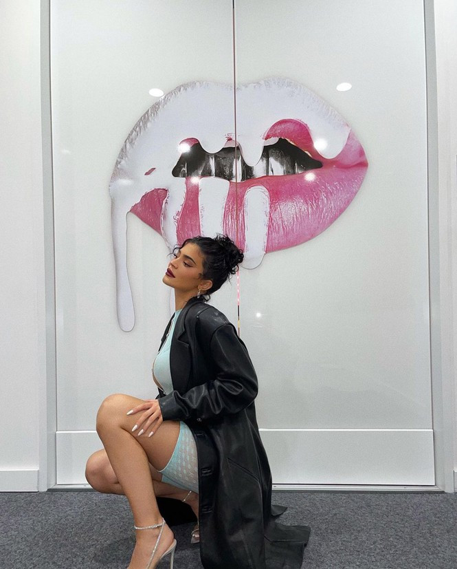 Set đồ được cô mix đồ khá tinh tế với kiểu áo choàng da màu đen và đôi guốc quai ánh bạc lấp lánh 