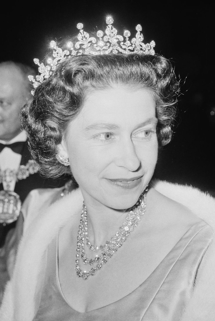 Nữ hoàng đội vương miện Girls of Great Britain and Ireland Tiara cùng với chiếc vòng cổ 3 sợi kín đặc kim cương tới Học viện Nghệ thuật Sân khấu Hoàng gia năm 1964. 