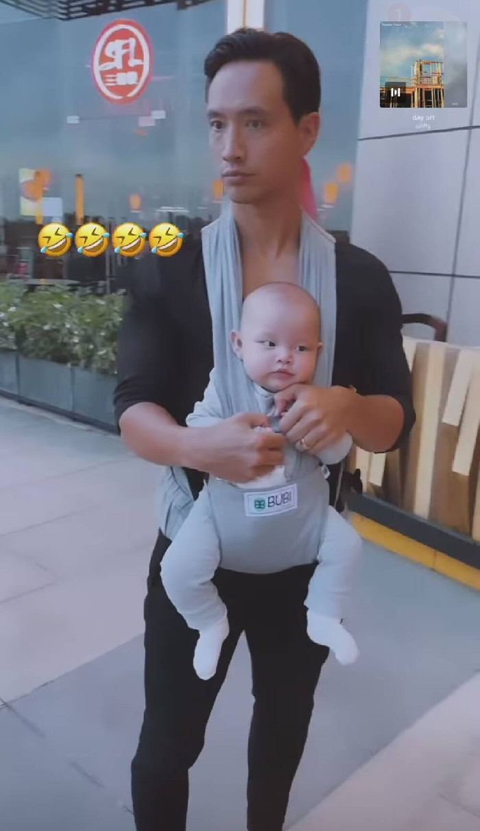 Kim Lý cùng Hà Hồ địu con xuống phố, chồng bế con trai, vợ ôm con gái.