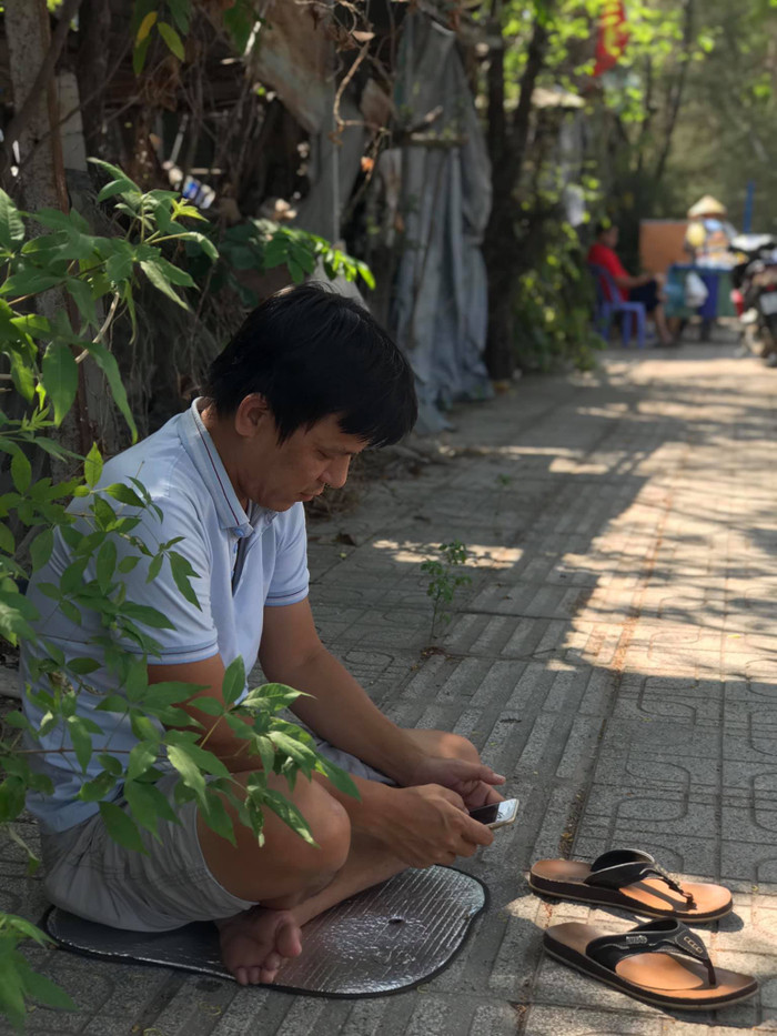 Anh Hiếu tận dụng bóng mát ngồi nghỉ ngơi trong lúc đợi con trai hoàn thành bài thi