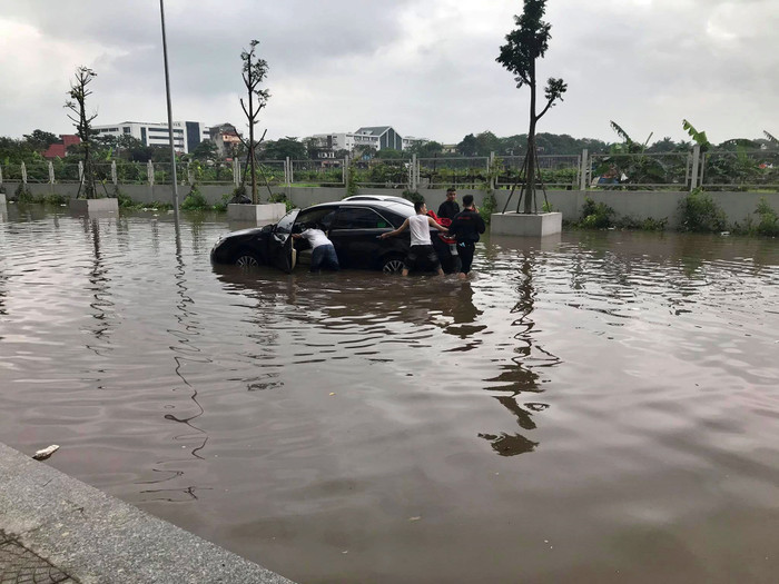 Một số người dân cố gắng giải cứu xe ô tô ngâm trong dòng nước.