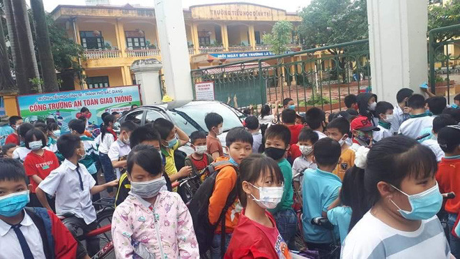 Chiếc xe ô tô đậu ngay cổng chính của trường học khiến việc di chuyển của các em học sinh gặp trở ngại