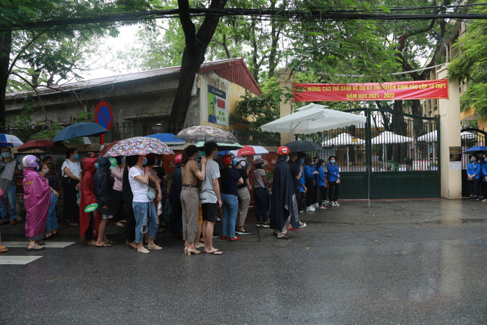 Bất chấp thời tiết Hà Nội có mưa lớn kéo dài, các bậc phụ huynh vẫn đứng dưới mưa ngoài cổng trường đợi con em mình hoàn thành bài thi.