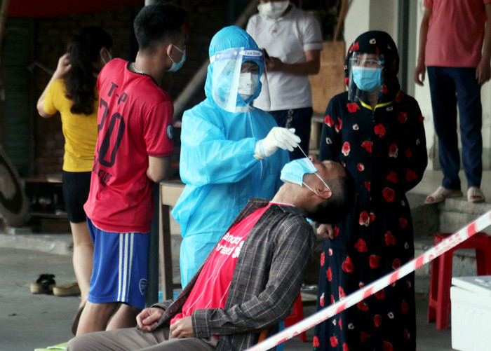 Cán bộ y tế lấy mẫu xét nghiệm cho các tiểu thương và người dân trong khu vực chợ đầu mối Vinh