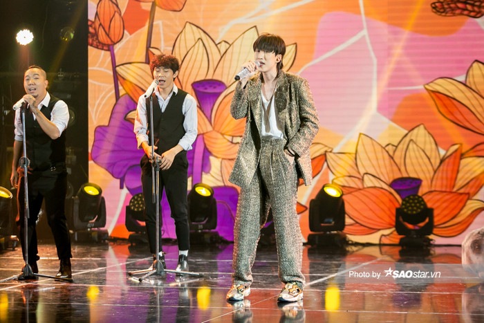 VP Bá Vương diện cả suit với chất liệu vải thô màu nâu kết hợp với áo trắng ba lỗ bên trong cùng giày thể thao nhí nhố