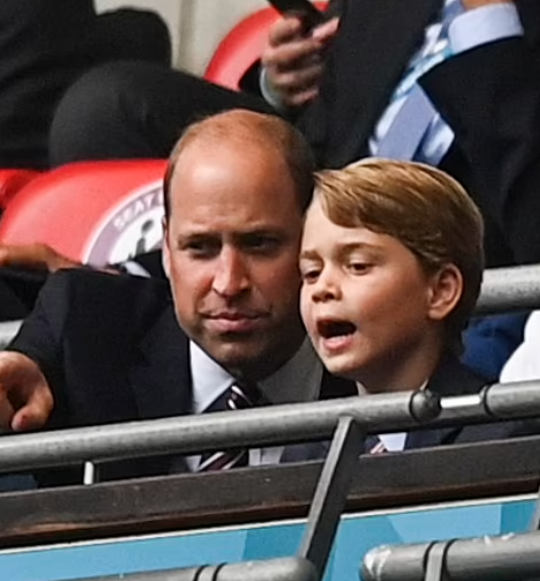 Hoàng tử William nghiêng người trò chuyện cùng con trai, ánh mắt của cả hai không rời quả bóng.
