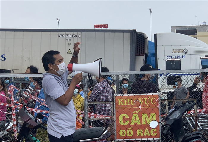 Quản lý chợ nhắc nhở các tiểu thương xếp hàng và giãn cách. Ảnh: Lao Động