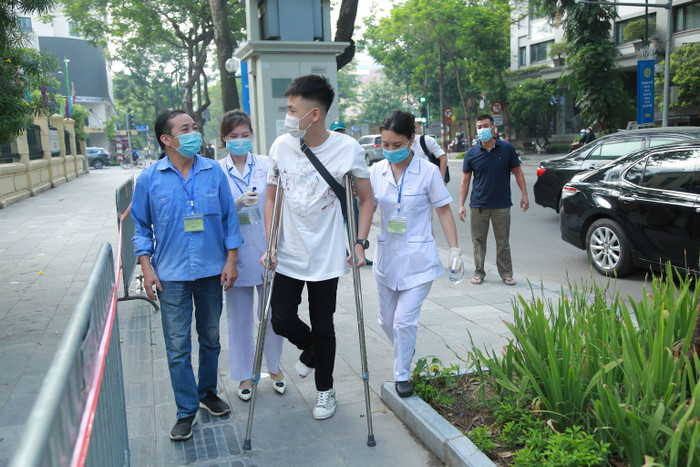 Nam sinh bị gãy chân được sự hỗ trợ từ lực lượng làm nhiệm vụ đưa vào phòng thi