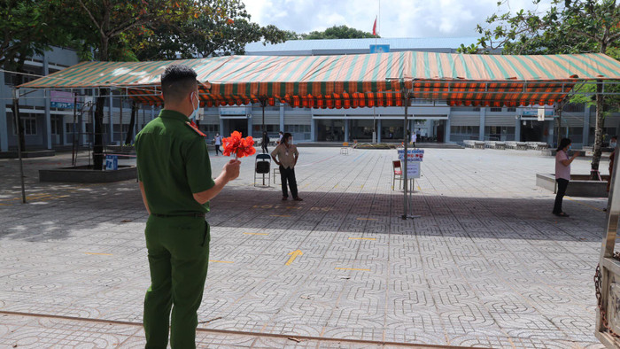 Anh chiến sĩ công an với bó hoa đỏ rực trên tay đứng đợi thí sinh ra khỏi phòng thi đầu tiên
