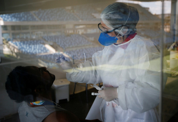 Một nhân viên y tế lấy mẫu xét nghiệm Covid-19 cho công nhân. Ảnh minh họa: REUTERS