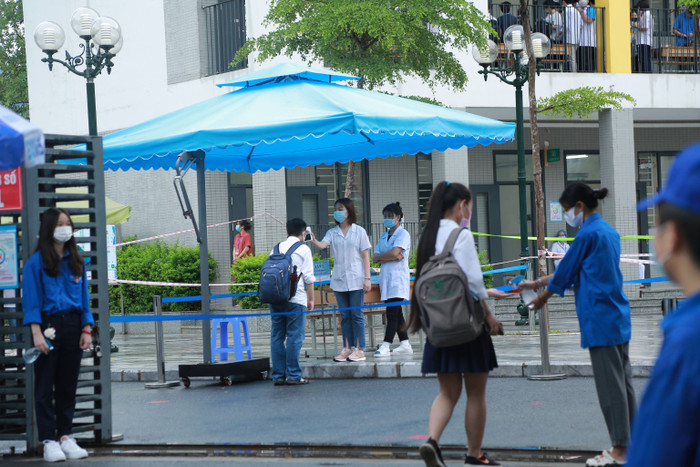 Thí sinh trước khi vào bên trong điểm thi được đo nhiệt độ, xịt sát khuẩn