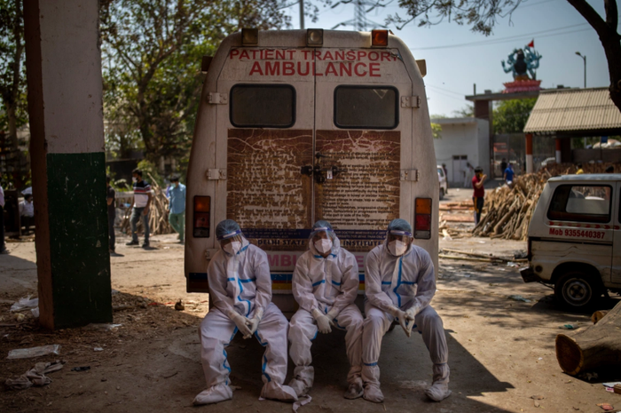Giây phút nghỉ ngơi hiếm hoi của những nhân viên dọn xác trước nhà hoả táng ở New Delhi, Ấn Độ.
