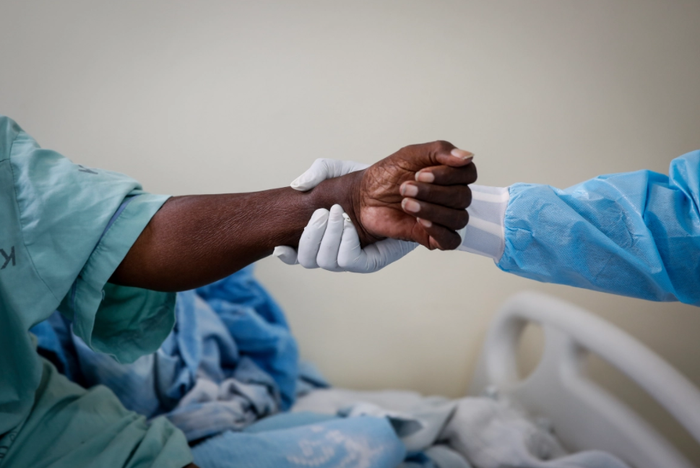 Một nhân viên y tế giúp bệnh nhân Covid-19 ngồi dậy trong phòng chăm sóc đặc biệt tại Bệnh viện Quốc gia Kenyatta, Nairobi, Kenya.