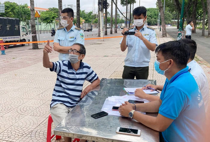 Người đàn ông (áo kẻ) đi tập thể dục ở công viên bị lực lượng chức năng lập biên bản. Ảnh: Zing.vn