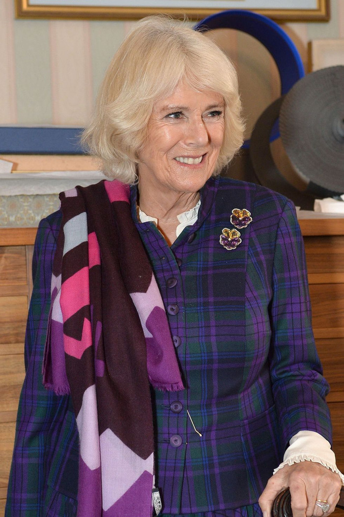 Nữ công tước xứ Cornwall đeo một cặp hoa cài áo bằng thạch anh tím và tráng men màu vàng trong chuyến thăm Greenwich năm 2019.