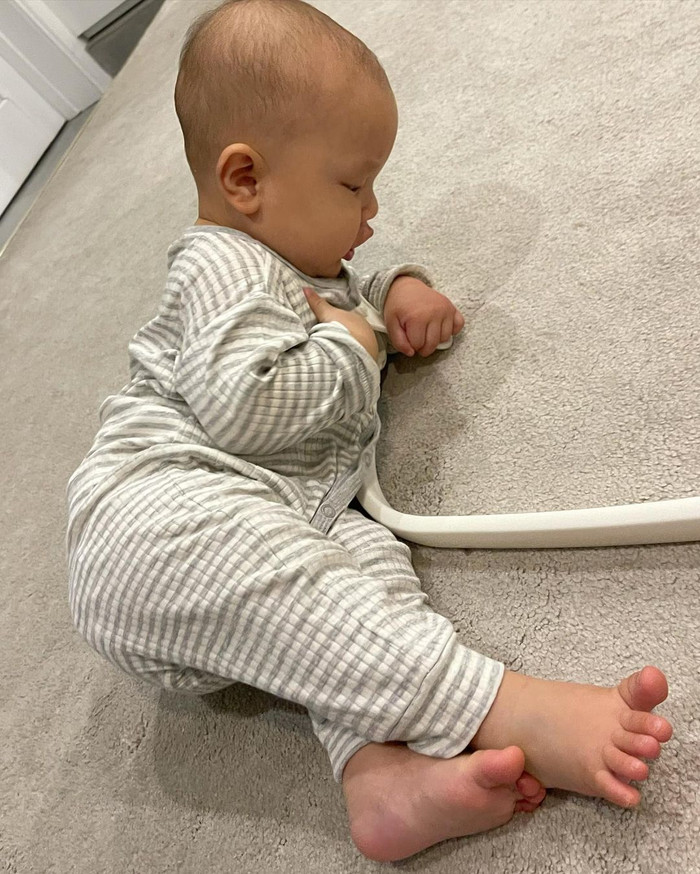 Cậu nhóc nằm dài trên thảm và 'nghiên cứu' cách chơi đồ chơi.