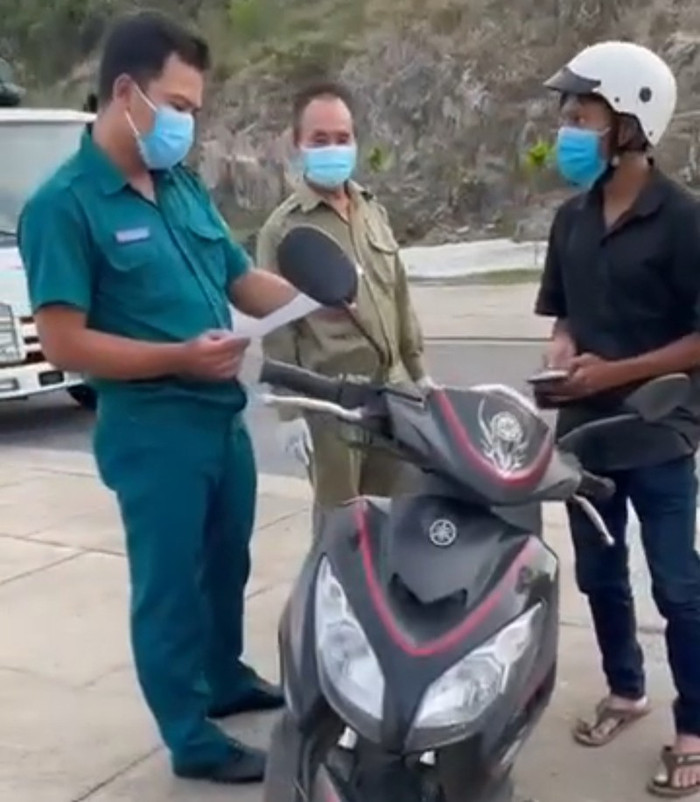 Nam thanh niên (áo đen) bị cán bộ phường Vĩnh Hòa giữ xe, tịch thu giấy tờ vì ra ngoài mua bánh mỳ, nước uống. Ảnh cắt từ clip