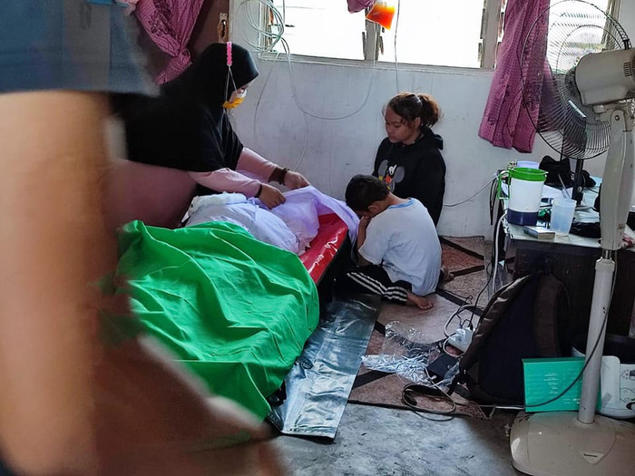 Các con ngồi bên cạnh thi thể mẹ vừa qua đời.