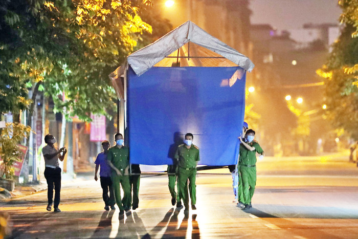 Lực lượng chức năng khiêng lều dã chiến lập chốt phong toả Bệnh viện Phổi Hà Nội vào đêm 25/7 để phòng chống dịch bệnh.