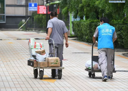 Tình nguyện viên giao nhu yếu phẩm cho người bị cách ly ở thủ đô Bắc Kinh hôm 3-8. Ảnh: Tân Hoa Xã