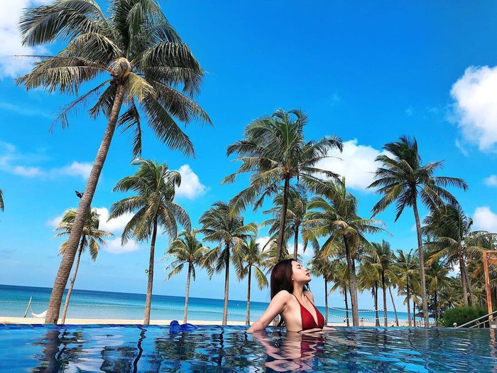 Đi du lịch biển, Thiên An không quên hút hồn mọi người với hình ảnh diện bikini đỏ nổi bật thả dáng bên bể bơi ngoài trời trong khu resort.