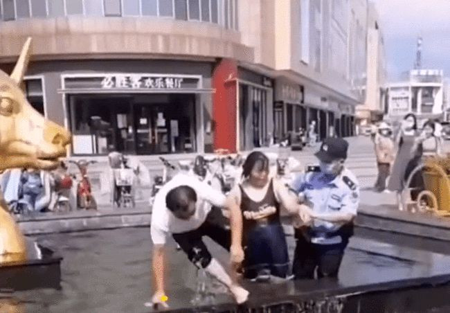 Khoảnh khắc cảnh sát lôi cô gái ra khỏi hồ phun nước. 