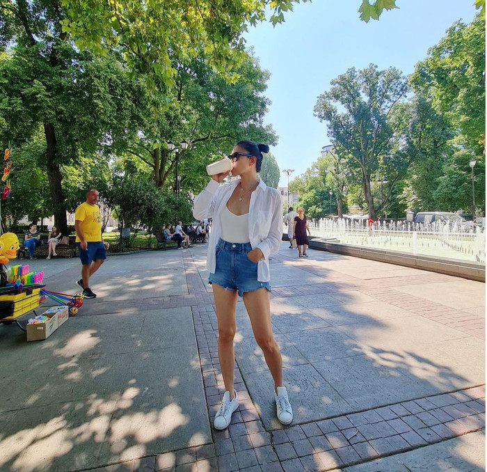 Trang phục đậm chất mùa hè của Ngô Thanh Vân với áo tank top mix short jeans cạp cao mặc ngoài cùng sơ mi oversized và sneaker trắng