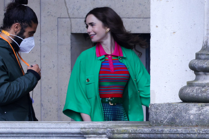 Bộ cánh tắc kè bông nhưng mặc lên người Emily lại vô cùng hợp lý. Cô khoác áo màu xanh lá ra ngoài chiếc áo polo dệt kim nhiều màu sắc, thêm một điểm nhấn là thắt lưng có khóa kim loại. Đây là trang phục công chúa, màu mè đậm chất Patricia Field chỉ có thể áp dụng trên màn ảnh rộng.