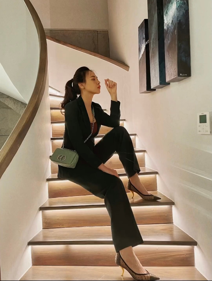 Địa điểm 'sống ảo' của Đàm Thu Trang tiệp tục được đổi sang góc cầu thang với set đồ vest màu đen.
