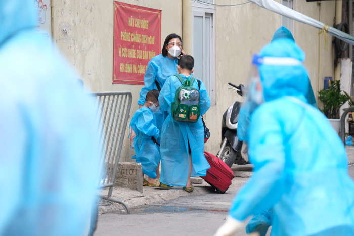 Em nhỏ đứng cùng mẹ đang chờ đi cách ly.