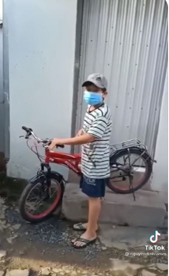 Bé trai đứng cạnh chiếc xe màu đỏ xuất hiện trong clip đối thoại với chú CA.