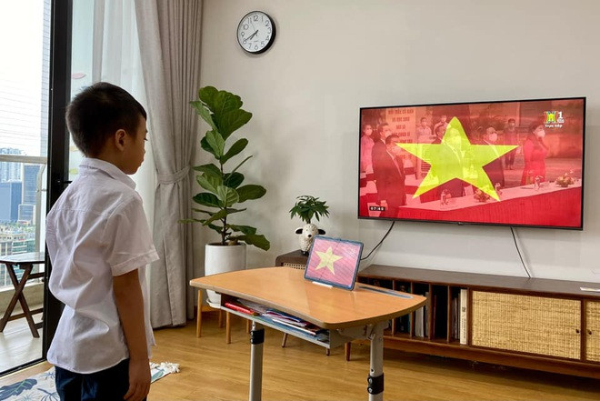 Đúng 7h30, Nguyễn Nam Khánh (7 tuổi, hs lớp 2A5 trường tiểu học Yên Hòa, Cầu Giấy) dự lễ chào cờ, khai giảng năm học mới cùng toàn bộ học sinh TP Hà Nội qua hình thức online, theo dõi qua cả Truyền hình Hà Nội và ipad kết nối với cô giáo, các bạn ở lớp. Nguồn: Dân Trí
