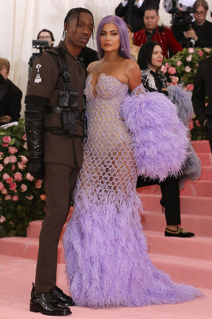 Kylie Jenner mặc một chiếc váy tím vô cùng nổi bật của Versace. Travis Scott mặc đồ màu tối để không lấn át người yêu nhưng trang phục của anh vẫn được đính phụ kiện cầu kỳ, phản ánh đúng cá tính người mặc.  