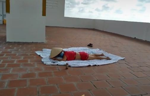 Bị nhắc nhở nhưng người phụ nữ vẫn tiếp tục nằm phơi nắng. 