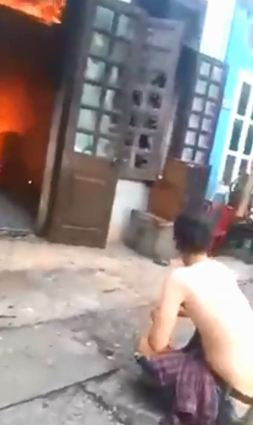 Nam thanh niên ung dung ngồi nhìn căn nhà đang bốc cháy. 