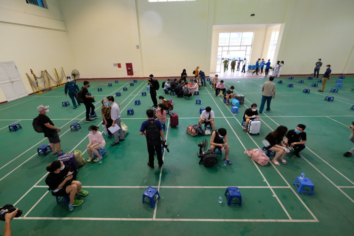 Người dân ngồi giãn cách tại các ghế đã được bố trí sẵn trong khu vực sàn thi đấu và đợi người nhà đến đưa về.