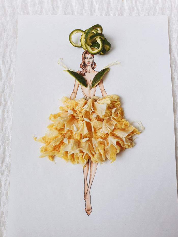 Mẫu thiết kế với phần nón và áo được làm từ vỏ cam sành cùng hạt cam phơi khô, chân váy là các tép cam đã vắt nước. 