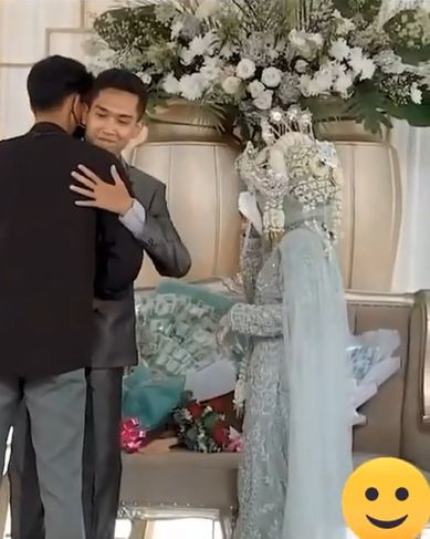 Chú rể cố nặn ra một nụ cười khi người yêu cũ của cô dâu ôm mình. 