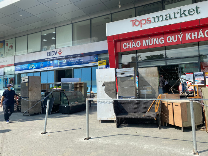 Một nhóm người mang bàn ghế, tủ đến để phía trước cửa toà nhà.