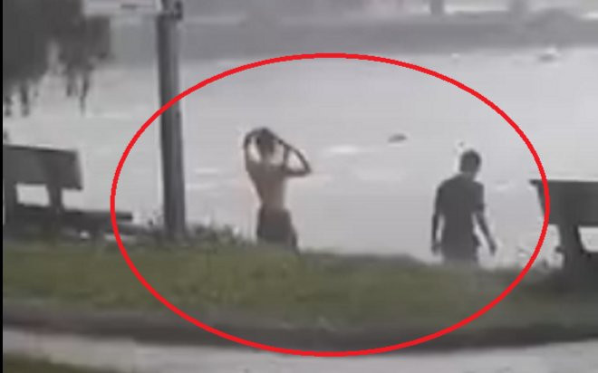 Đôi nam nữ dắt díu nhau ra hồ nước tắm giữa trời mưa tầm tã khiến dân tình khó hiểu Ảnh 2