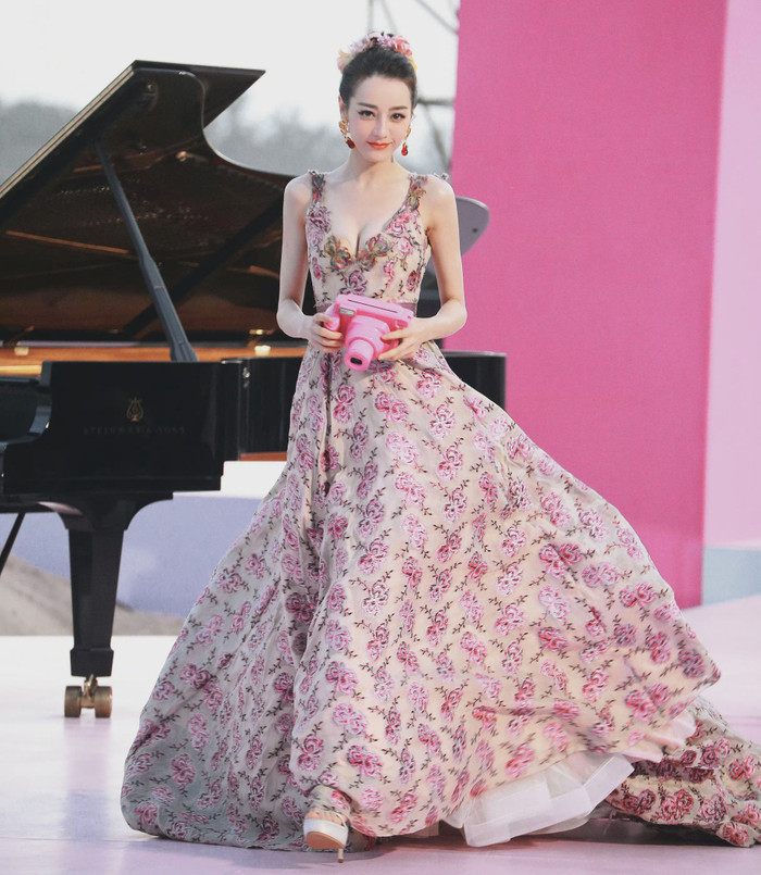 Cũng lựa chọn chiếc váy tông hồng giống đàn chị nhưng Địch Lệ Nhiệt Ba lại vừa kiêu sa, vừa trẻ trung khi chọn máy ảnh hồng làm phụ kiện.