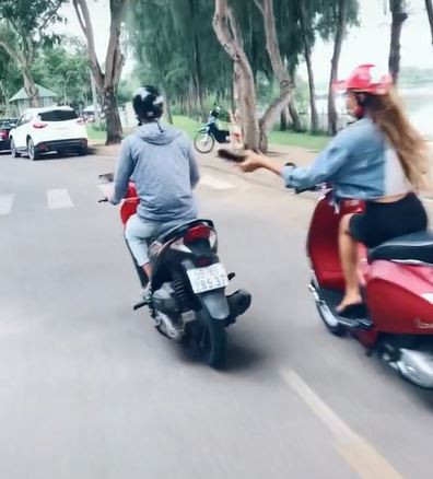 Cô gái cầm guốc chuẩn bị đánh nam thanh niên đi xe máy phía trước. 