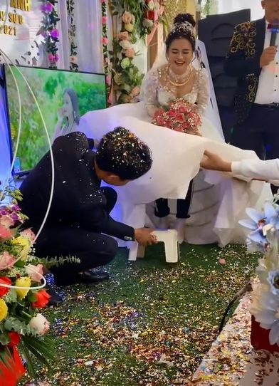 Chú rể vén váy cô dâu lên cao để đặt ghế vào bên trong. 