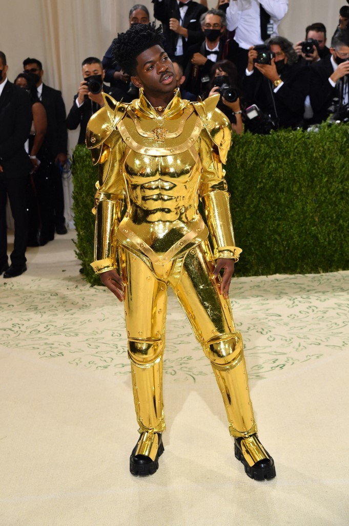 Ca sĩ Lil Nas X cũng gây chú ý với tài biến hóa trang phục linh hoạt khi xuất hiện tại Met Gala 2021. Ban đầu, anh diện áo choàng khổng lồ, sau đó, ca sĩ cởi ra, để lộ bộ giáp vàng như chiến binh của Versace. 