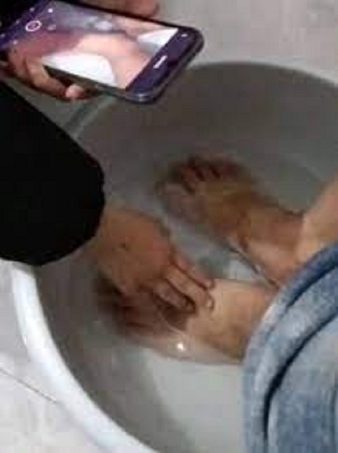 Bé gái cúi xuống rửa chân cho bố.