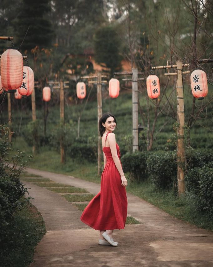 Lối vào khu nghỉ dưỡng treo lồng đèn đỏ dọc hai bên. Cô chọn mẫu váy đỏ phù hợp với khung cảnh nơi đây.