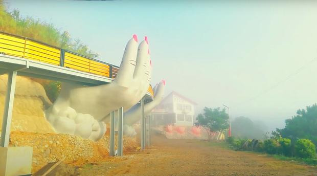 Cũng tạo dáng bàn tay đỡ lấy cầu nhưng những ngón tay của chiếc cầu này trông thô hơn, đặc biệt là phần móng tay còn được sơn màu đỏ chói.