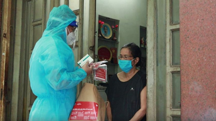 Người dân cần thông báo cho trạm y tế nếu tự xét nghiệm dương tính với COVID-19 để được nhân viên y tế tư vấn, hướng dẫn chăm sóc, điều trị kịp thời. Ảnh: Phát thuốc cho F0 điều trị tại nhà