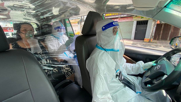 Tài xế và nhân viên y tế cấp cứu bệnh nhân F0 bằng xe taxi - Ảnh: TỰ TRUNG